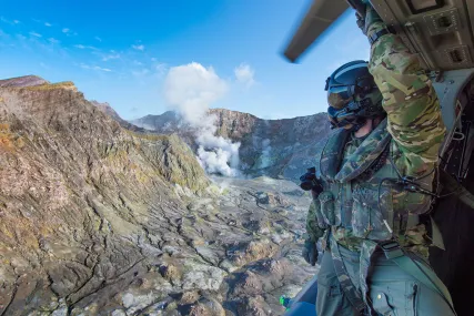 Helicopter Loadmaster Sergeant Sam Riordan surveys White Island during a reconnaissance flight. Helicopter Loadmaster Sergeant Sam Riordan surveys White Island during a reconnaissance flight.