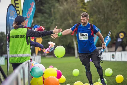 A man successfully completes Oxfam Trailwalker and crosses the finish line.