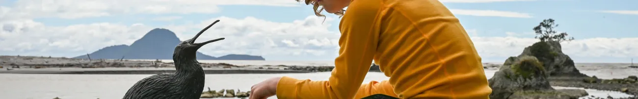 Kid sitting with Kiwi statue at the Heads