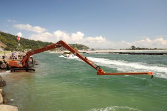 An earthmover with a six-metre extension boom dredges the Whakatāne River channel.